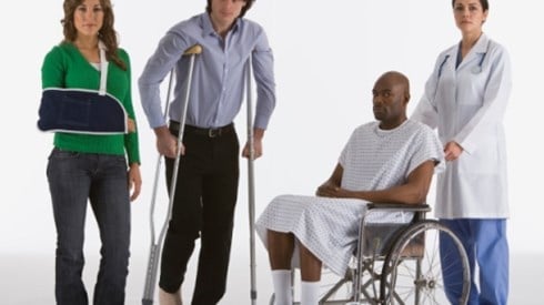 A woman with her arm in a sling, a man on crutches with a cast on his foot, and man in a wheelchair being pushed by a nurse