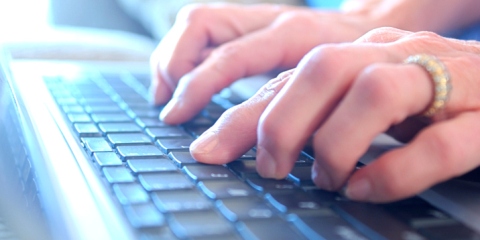 A view of a keyboard looking down across hands typing on keys