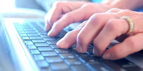 A view of a keyboard looking down across hands typing on keys