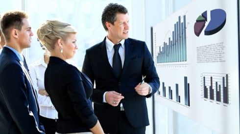 Business people meeting looking at charts and graphs displayed on screen