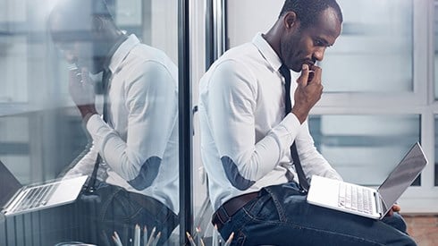 Office worker contemplating online educational certifications while looking at this laptop