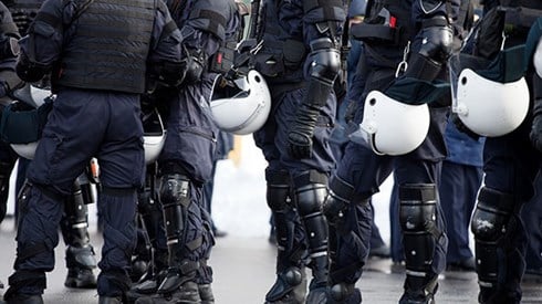 Line of riot police holding helmets in hand