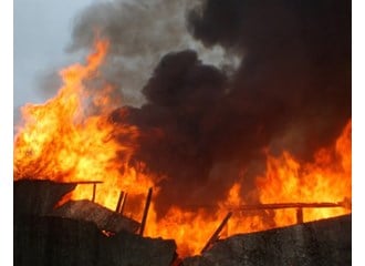 A building is being consumed by large flames of fire and black smoke.