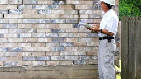 Man in hard hat evaluating foundation damage