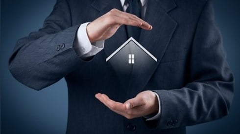Businessman with his hands protecting a hologram of the top of a house