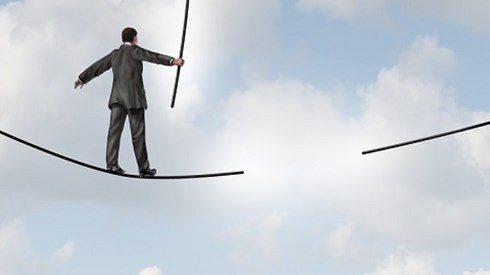 A businessman in the clouds is walking on a tightrope using a balancing pole and will approach a section that has disappeared