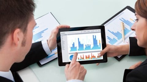 Two business professionals review statistical analysis reports that are printed out and on a tablet