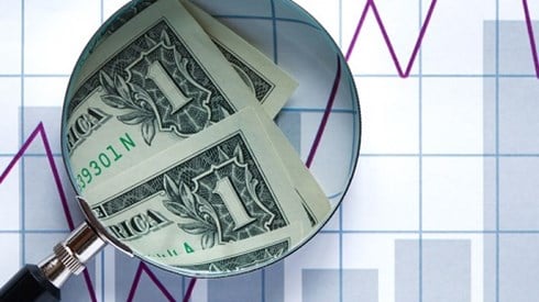 Dollar bills viewed through magnifier with graph in background