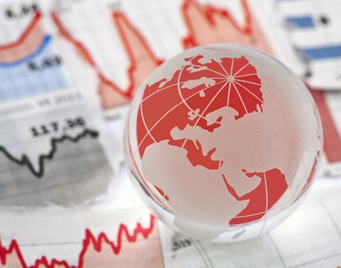 Red and white globe sitting on top of investment data graphs on paper