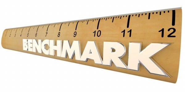 A tan 12-inch ruler with black inch markers and the word BENCHMARK in white letters stretching to the end on white background