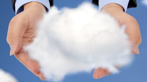 The hands of a business professional are in the sky and are holding a large puffy cloud