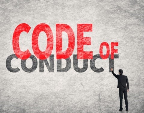 A full-sized businessman standing and pointing to the giant phrase CODE OF CONDUCT