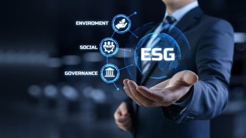 Businessman holding the acronym ESG in a bubble with adjoining bubbles reading environmental, social, and governance