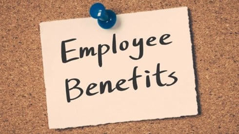 The words Employee Benefits pinned to a cork board with a blue push pin