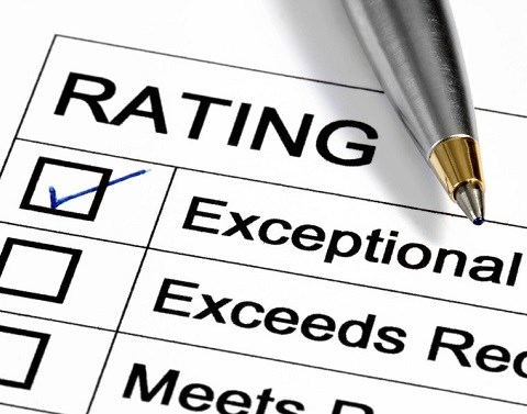 A pen rests on the top left corner of a Performance Review Rating sheet and the Exceptional rating is checked.