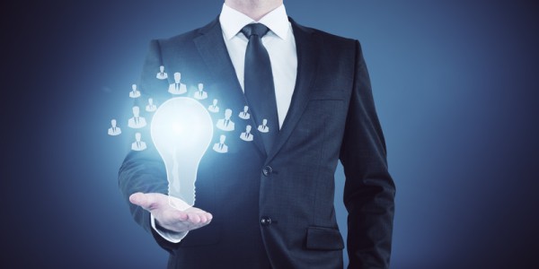 In the outstretched palm of a businessman is an illuminated lightbulb with icons of business professional resume poses