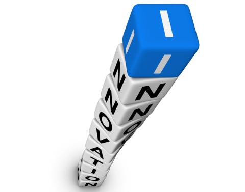 White dice with letters are stacked to spell the word INNOVATION with the top blue dice showing the letter I.