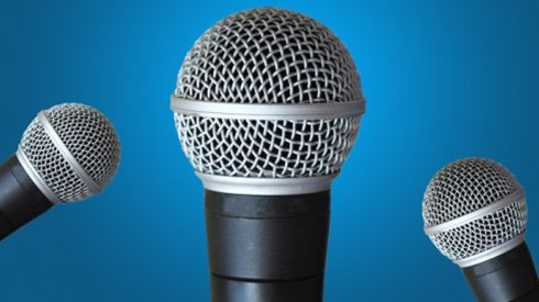 3 microphones with 1 in front and 2 to the sides in front of a blue background