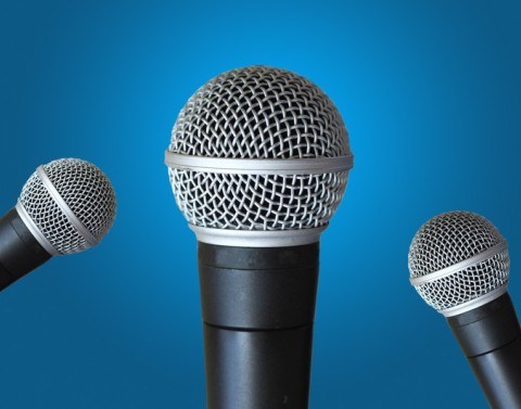 3 microphones with 1 in front and 2 to the sides in front of a blue background