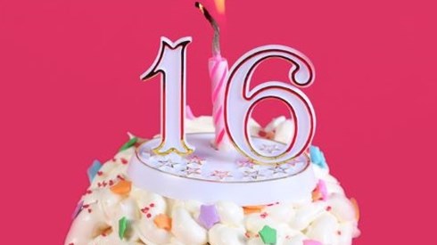 A cupcake with a number 16 topper and a lit candle