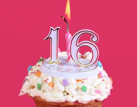 A cupcake with a number 16 topper and a lit candle