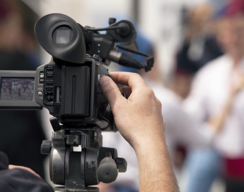 Photographer with a professional camera is filming blurred-out persons
