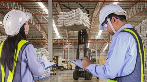 Warehouse Supervisors wearing Hardhats and Reflective Vests Monitor Forklift Safety Using Checklists