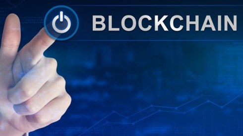 Hand pushing power button next to word Blockchain