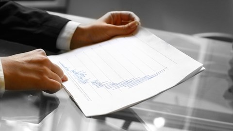 A businessman's hands holding a paper with a report showing an increasing graph