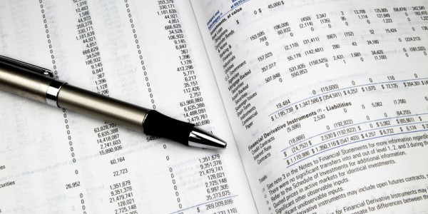 Two pages open on a printed and bound annual investment report with a black and silver pen sitting on top