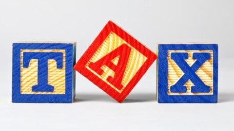 Wooden building blocks spelling out the words TAX in blue and red letters