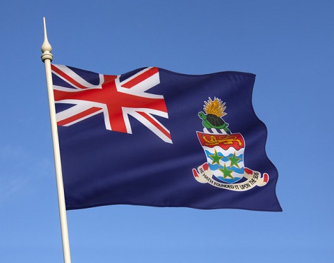 Cayman flag flying on a pole with a blue sky background