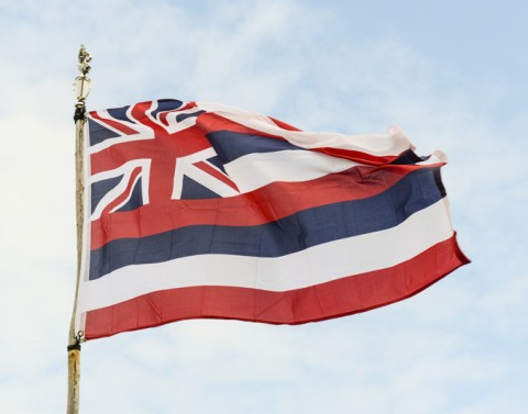 The flag of Hawaii with eight stripes of white, red and blue and the flag of Great Britain is in the upper left corner