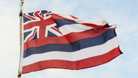 The flag of Hawaii with eight stripes of white, red and blue and the flag of Great Britain is in the upper left corner