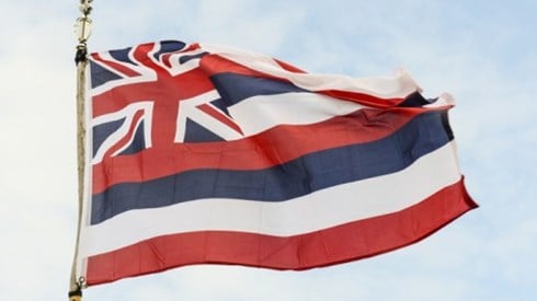 The flag of Hawaii with eight stripes of white, red and blue and the flag of Great Britain is in the upper left corner