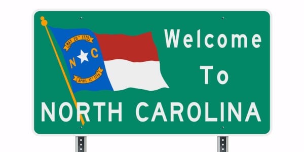 Road sign saying Welcome to North Carolina and featuring the state flag
