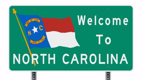 Road sign saying Welcome to North Carolina and featuring the state flag