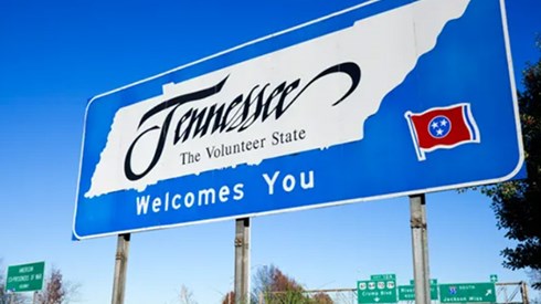 Blue road sign with silhouette of state of Tennessee and "Tennessee, the volunteer state, welcomes you" written on it.  