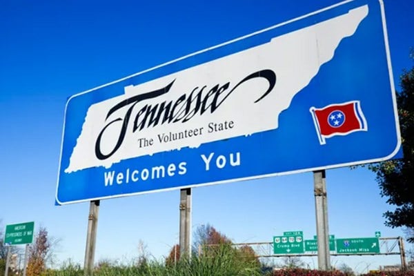 Blue road sign with silhouette of state of Tennessee and "Tennessee, the volunteer state, welcomes you" written on it.  