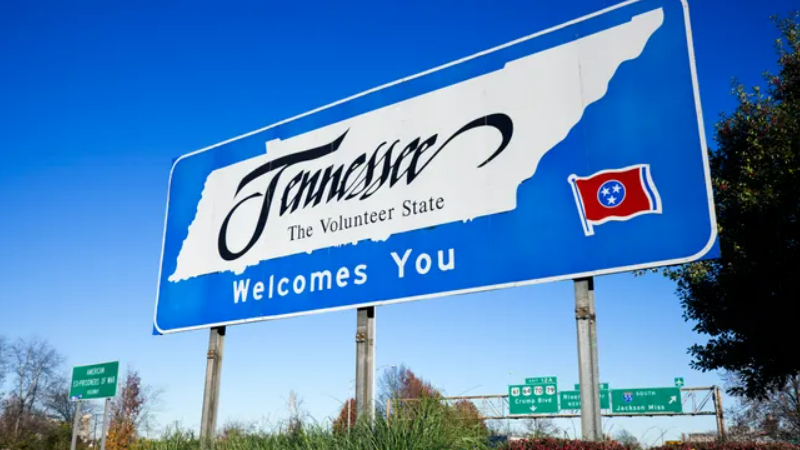 Blue road sign with silhouette of state of Tennessee and "Tennessee, the volunteer state, welcomes you" written on it.  