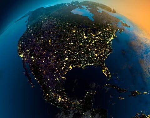Global view of North America at night as viewed from space with lights showing in the cities with sunrise approaching in the east