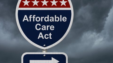 Highway sign for the Affordable Care Act with 5 white stars above and an arrow pointing right below amid dark skies