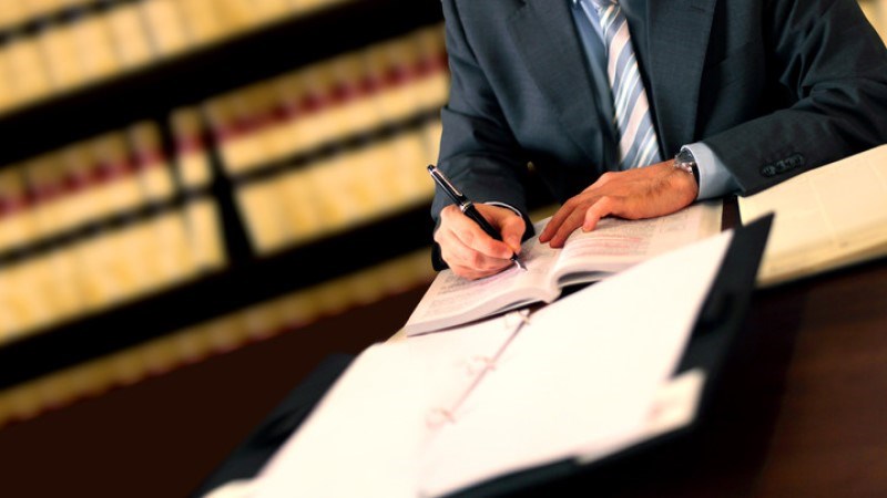 Lawyer working at a table with law books in the background