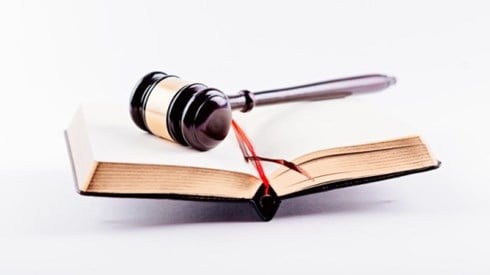 A gavel is lying on top of a open bound book