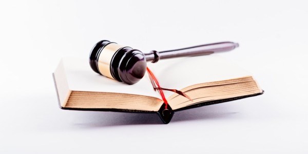 A gavel is lying on top of a open bound book