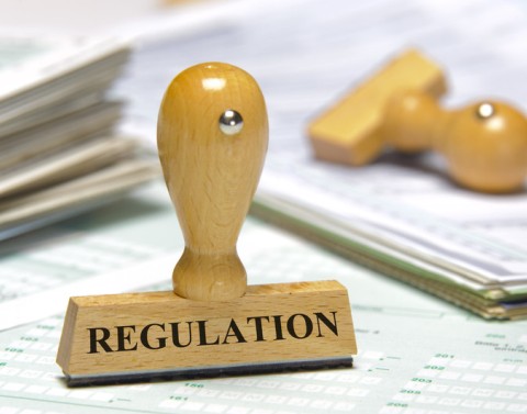 Wood rubber stamp for REGULATION on top of and surrounded by blank forms