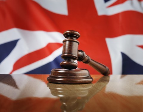A gavel lying on its base on a desk with the Union Flag of the United Kingdom in the background