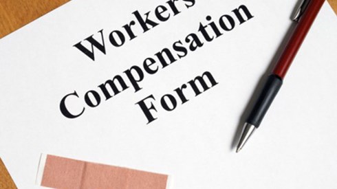 Workers Compensation Claim Form cover page with a pen and an adhesive bandage.