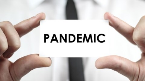 Businessman holding a small piece of paper with the word Pandemic spelled in all caps