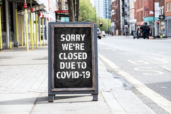 Sorry Closed for COVID-19 sign on standing sign on sidewalk